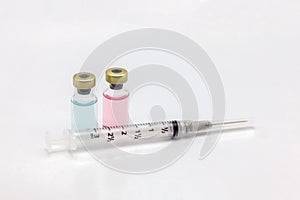 Two different isolated glass vaccine bottle with different colored liquid and an empty syringe