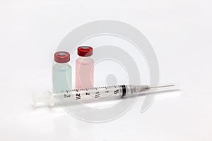 Two different isolated plastic vaccine bottle with different colored liquid and an empty syringe
