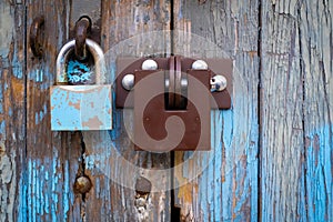 Two different locks on old wooden garage door, peeling paint, in