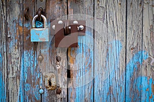 Two different locks on old wooden garage door, peeling paint, in