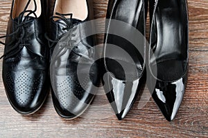 Two different Pairs of black classic modern shoes on the wooden floor background