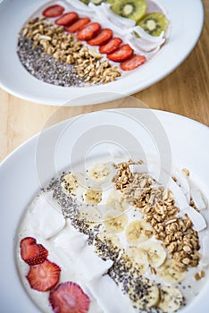 Two different Smoothie bowl with a selection of fruit granola, chia seed and coconut yogurt