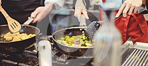 Two diligent chefs working in a hot kitchen cooking delicious food