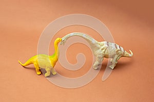 Two dinosaurs on a brown background. Plastic toys. Minimal design