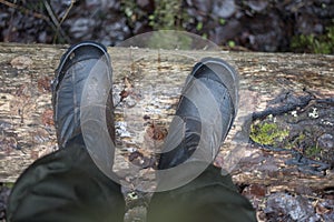 Two dirty boots on a damp old log in the forest mess