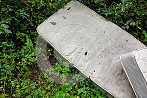 two dirty white sleeping mattresses discarded