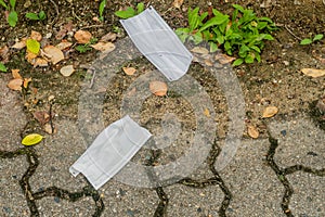 Two discarded medical mask on sidewalk