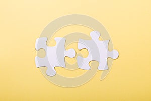 Two disconnected jigsaw puzzle pieces on yellow background White puzzle Concept success of business