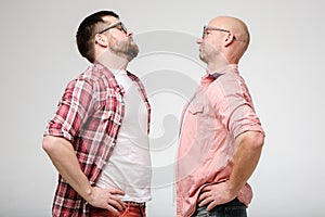 Two disgruntled men are standing face to face, arguing and arrogantly looking at each other.