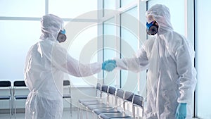 two disinfection specialists shaking hands in a decontaminated room.
