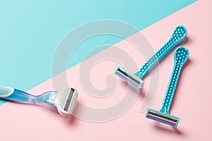 Two disposable blue razors and one reusable on pink background