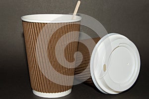 Two disposable cups for hot drinks on a dark backgrounds. Paper cups and white cap with the inscription Caution Contents Hot! .