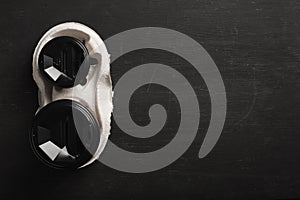 Two disposable paper cups of coffee and a disposable cup holder on a black wooden background