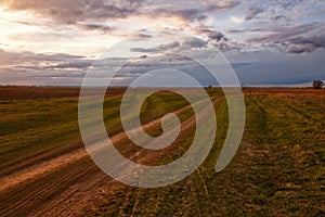 Two diverging dirt roads. A fork in two roads in a field in the late evening