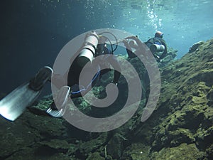Two divers exploring the cenotes in Mexico - Underwater at cenote Chac Mool in the Riviera Maya, Mexico photo