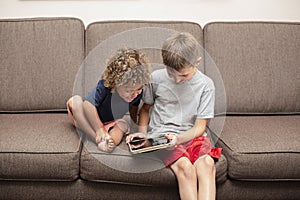 Two diverse boys playing together on a tablet computer