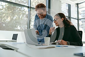 Two diverse business colleagues disscuss biz issue while use laptop in office background