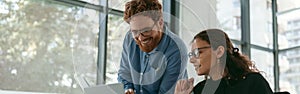 Two diverse business colleagues disscuss biz issue while use laptop in office background