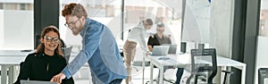 Two diverse business colleagues disscuss biz issue while use laptop in office background