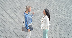 Two diverse business women talking to each other in a financial district. Business colleagues