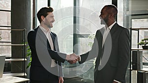 Two diverse businessmen multiracial business partners office coworkers men talking discuss negotiate project handshaking