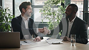 Two diverse businessmen at office meeting shake hands after successful business contract agreement. African businessman