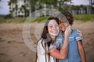 Two diverse cute kids smiling together on a beach outdoors,