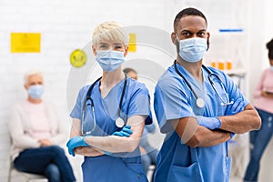 Two Diverse Doctors In Medical Masks Posing Standing In Hospital