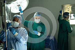 Two diverse female surgical techs adjusting light and iv bag in operating theatre during operation