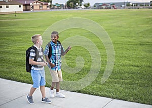 Two diverse school kids walking home together after school