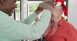 Two diverse senior male friends welcoming in doorway at christmas time