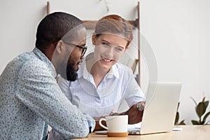 Two diverse smiling businesspeople discussing online project