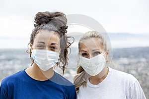 Two diverse women wearing personal protective equipment masks as they walk outdoors