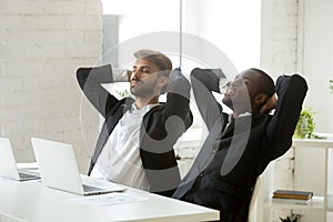 Two diverse young businessmen relaxing at work breathing fresh a