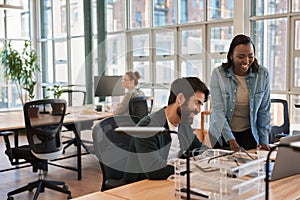 Two diverse young businesspeople smiling while working together on a laptop