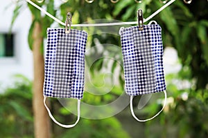 Two DIY handmade protective cloth fabric masks in Thailand hanging on clothesline.