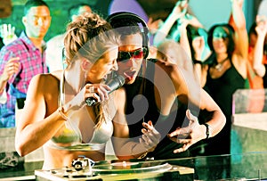 Two DJs in disco club, crowd background