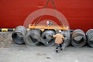 Two dockers fix a cargo of a wire for loading