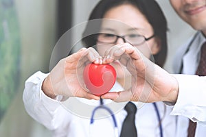 Two docter holding a red heart, health care concept.