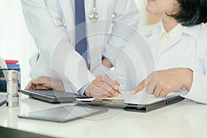 Two doctors analysing and consulting over medical record in mode