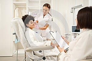 Two doctors consulting patient in beauty salon during procedure