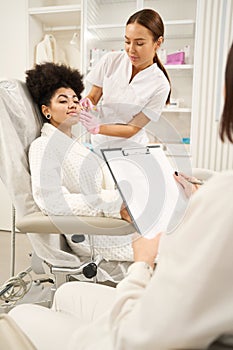 Two doctors consulting woman in beauty salon during procedure