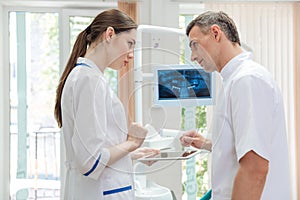 Two doctors dentists looking panoramic photo of teeth on monitor