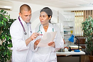 Two doctors discussing medical card of patient in office