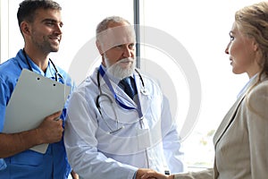 Two doctors and female patient shaking hands before consultation in the office of a modern medical center