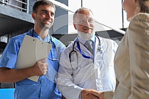 Two doctors and female patient shaking hands before consultation in the office of a modern medical center