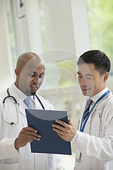 Two doctors looking down and consulting over medical record in the hospital