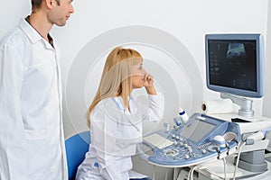 Two doctors looking at the ultrasonography divice