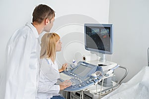 Two doctors looking at the ultrasonography divice