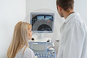 Two doctors looking at the ultrasonography divice